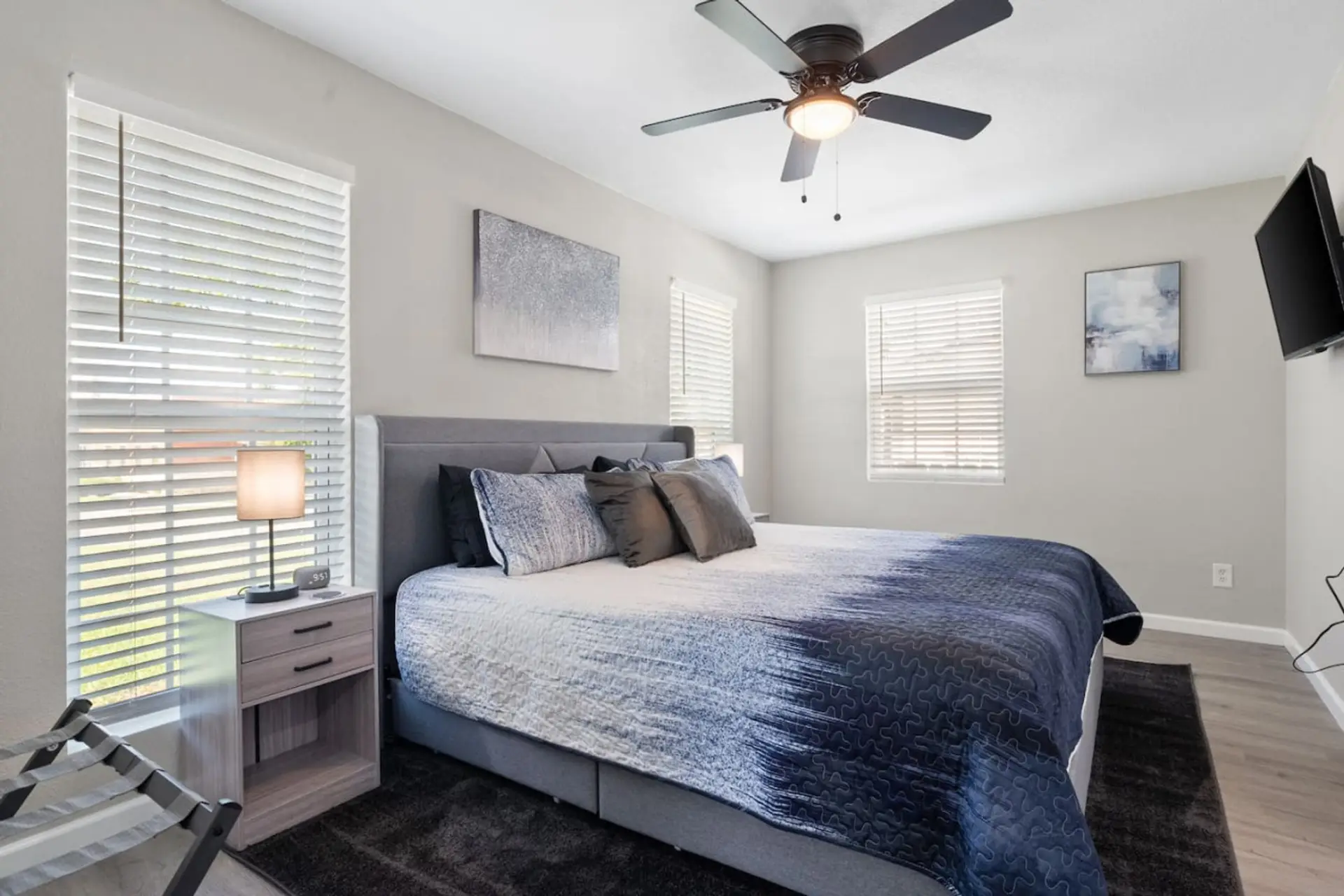 Primary bedroom at front of house, with King bed, en-suite bathroom, Smart Fire TV, nightstands with USB and Plugs, ceiling fan, and luggage rack