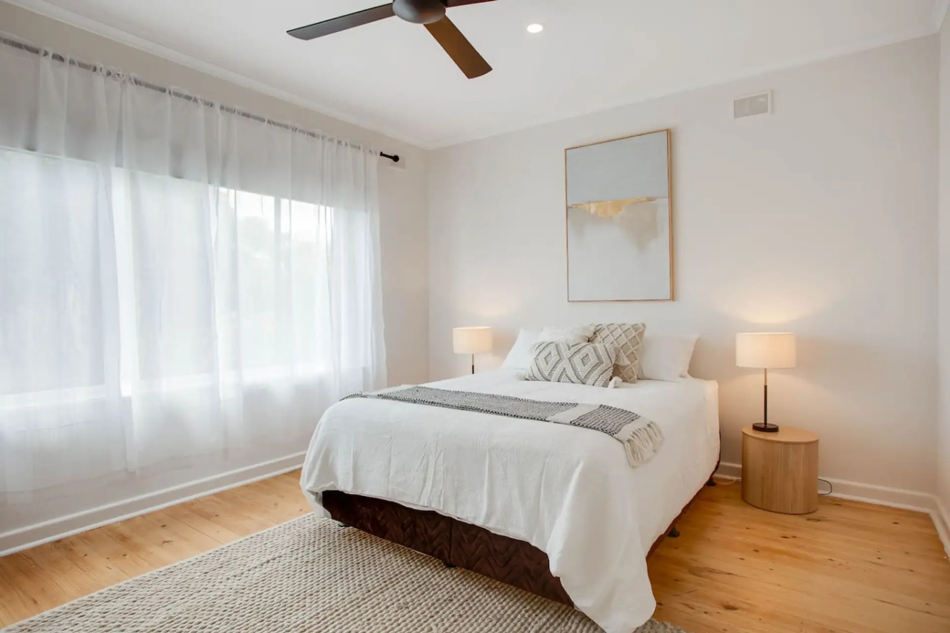 The primary bedroom promises restful nights with a queen bed, soft neutral styling, and a ceiling fan for quiet comfort.