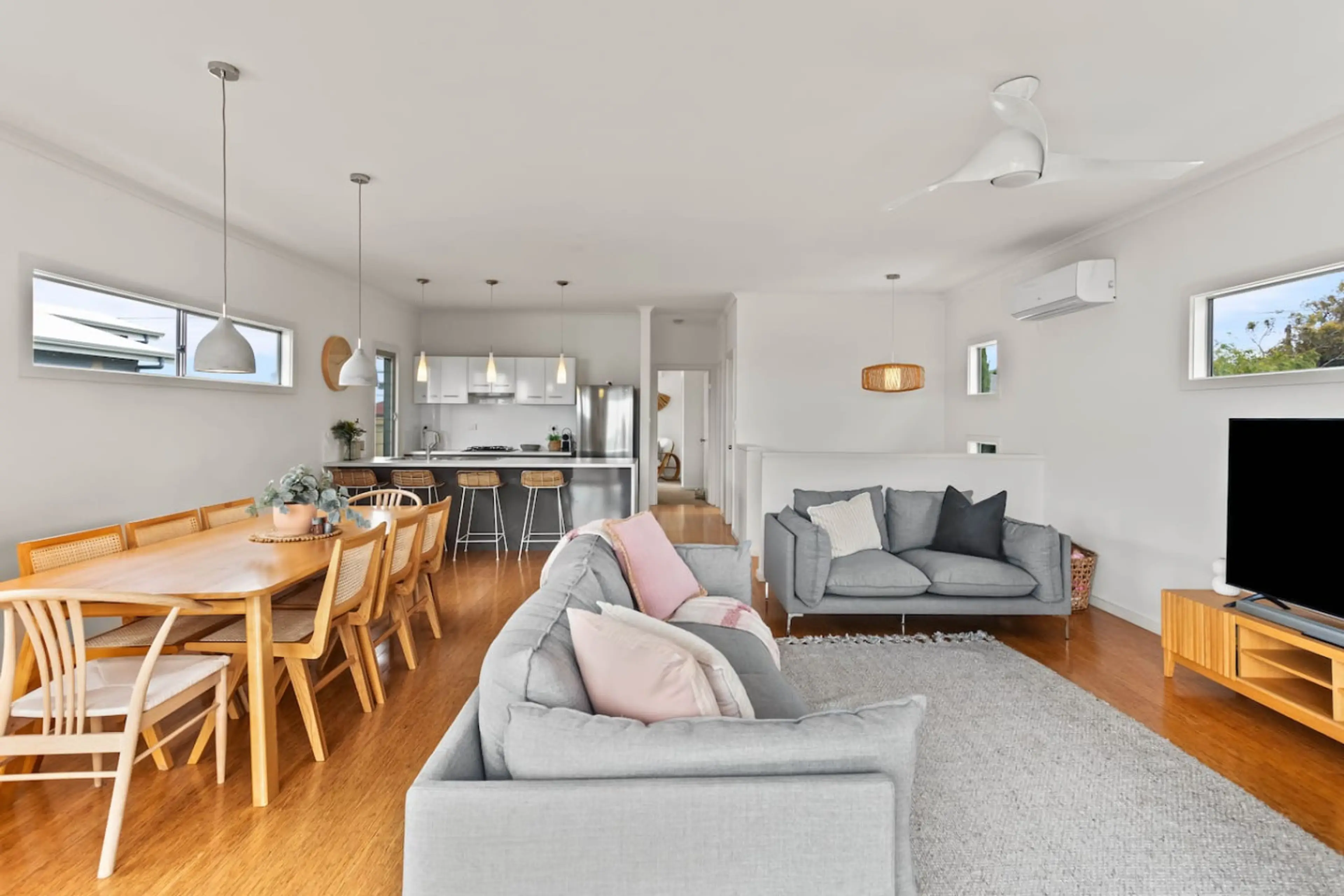 A bright, airy space where soft coastal tones, natural light, and comfortable seating invite you to unwind and flow seamlessly between lounging, dining, and balcony living.