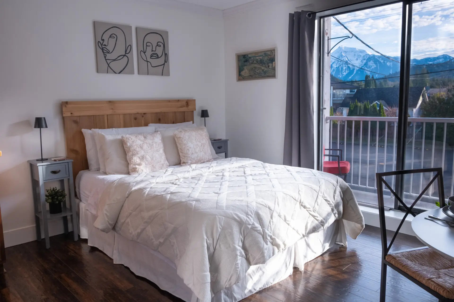 The cozy bed with white linens, next to the kitchenette.