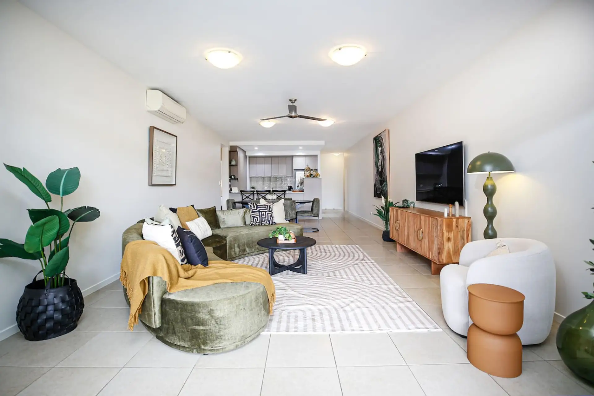 Open living area combining modern kitchen, dining, and lounge space with natural light and tropical charm.