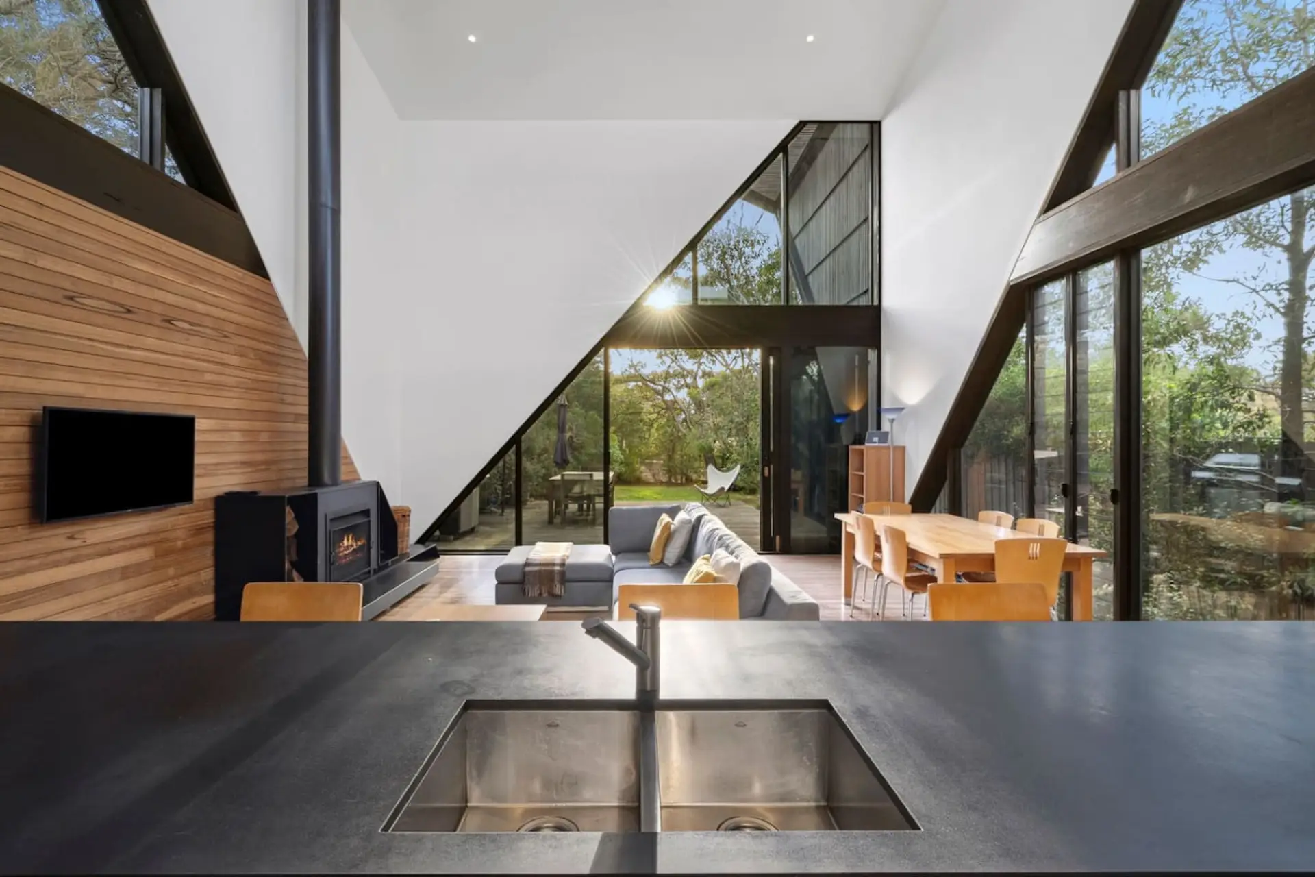 Expansive glass walls frame the open-plan living and kitchen space, filled with natural light and warmth.