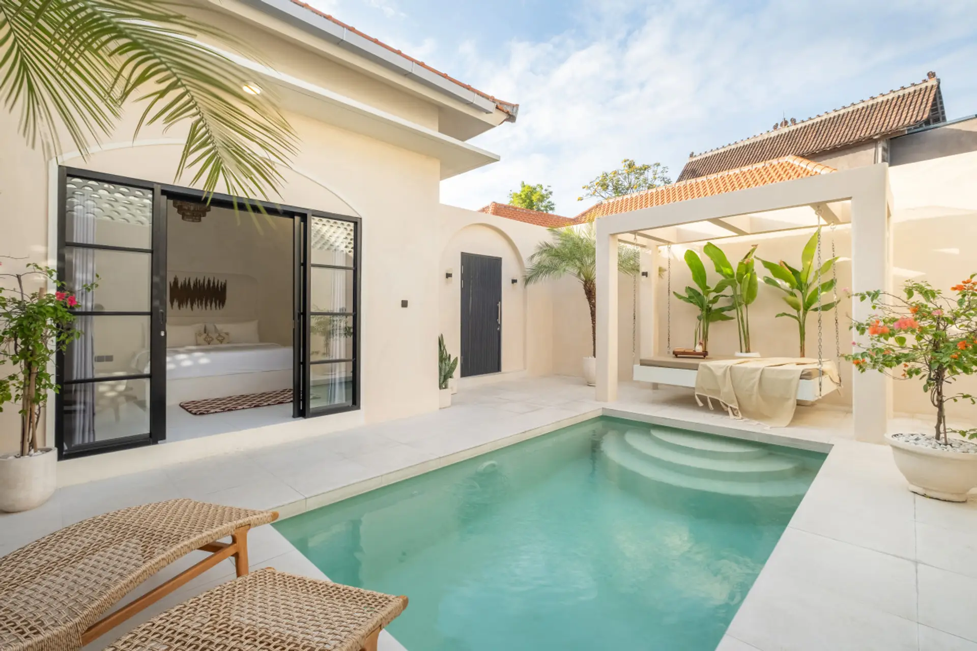villa courtyard with a cozy outdoor bed and a pool, basking under a clear blue sky.