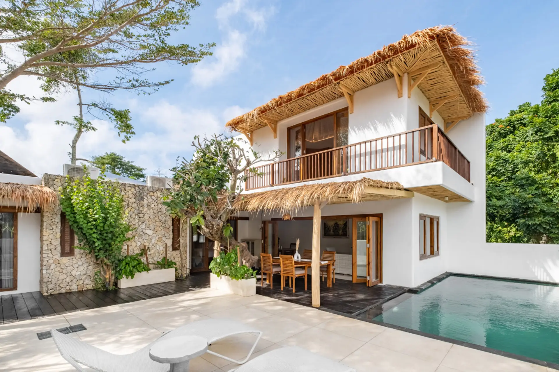 Tropical-style villa with thatched roof, stone accents, and private outdoor space