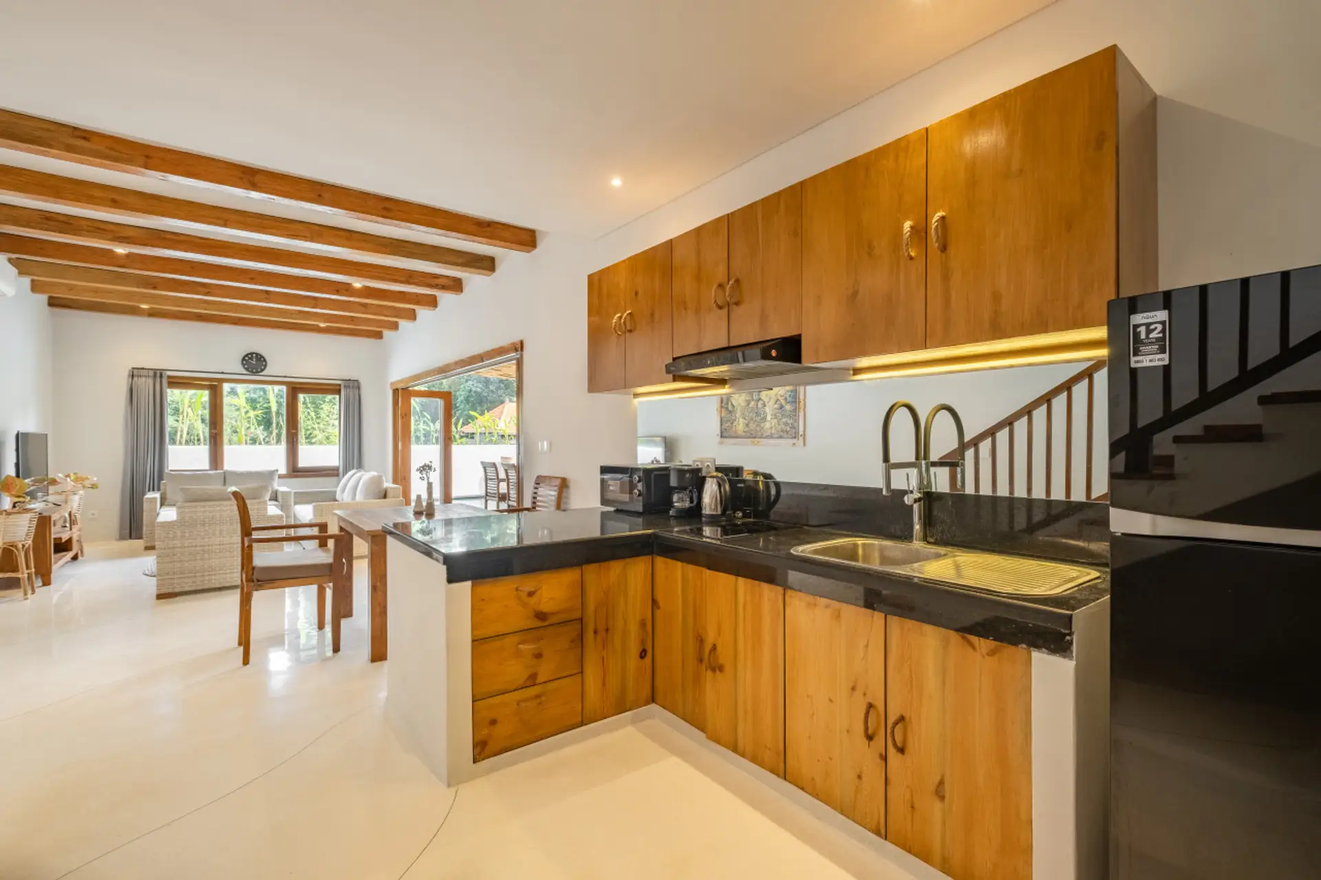 A compact kitchen featuring natural wood cabinets, dark countertops, and a mirrored backsplash, equipped with essential appliances for efficient use of space.