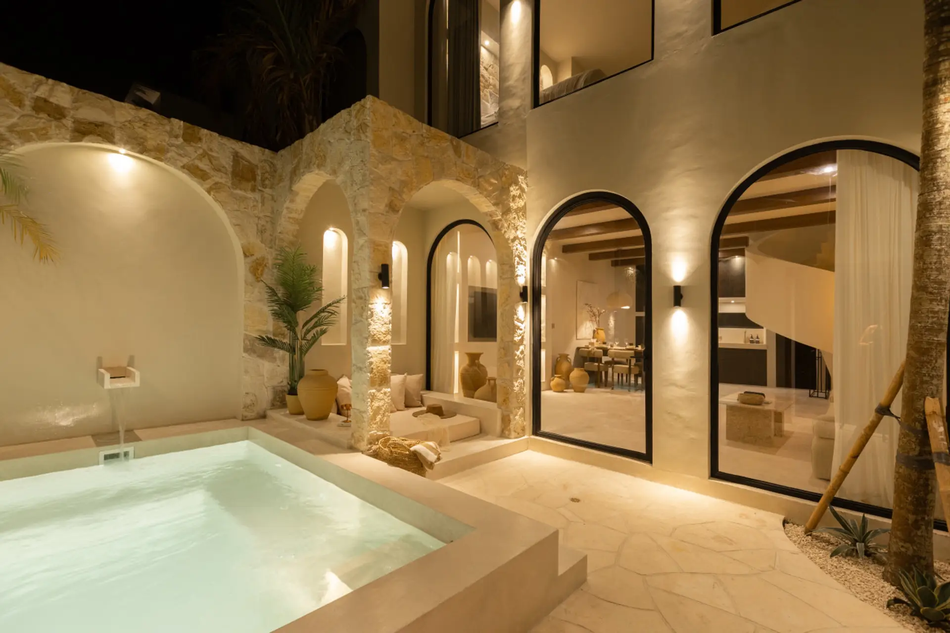 Elegant Mediterranean-style villa with warm stone textures, ambient lighting, and a private plunge pool for a serene evening retreat.