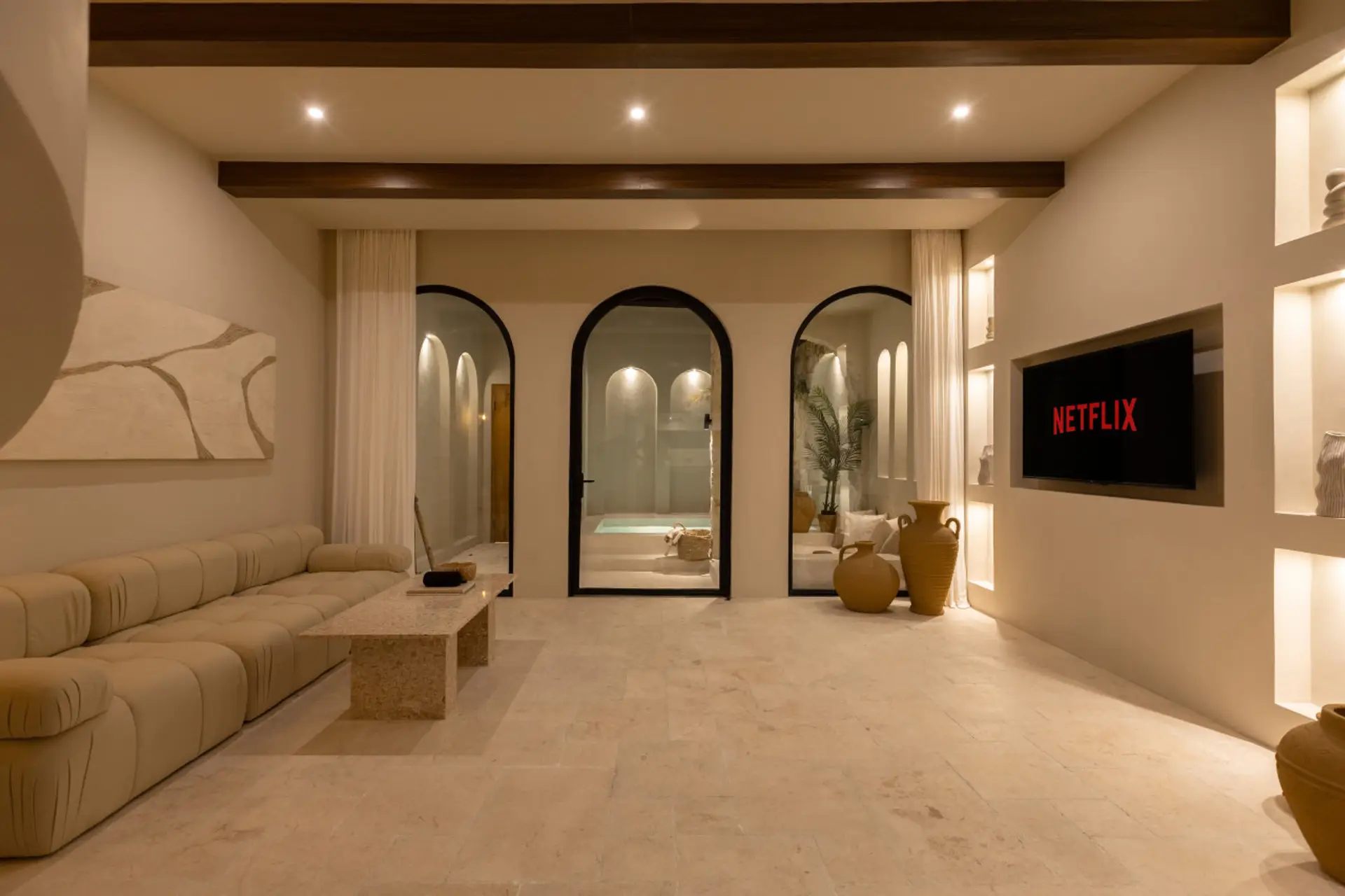 Luxurious living room with arched openings to a courtyard, sofa, and TV.