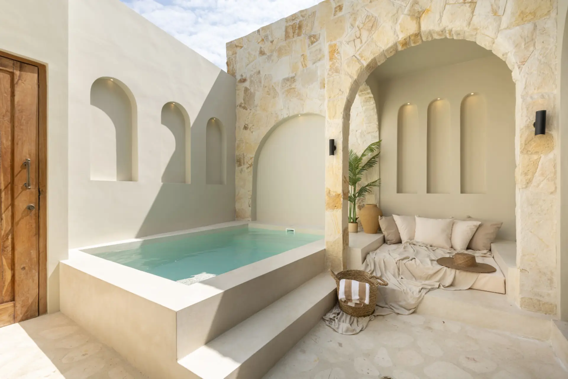 Bright Mediterranean-style courtyard with arched stone walls, cozy lounge, and private pool.