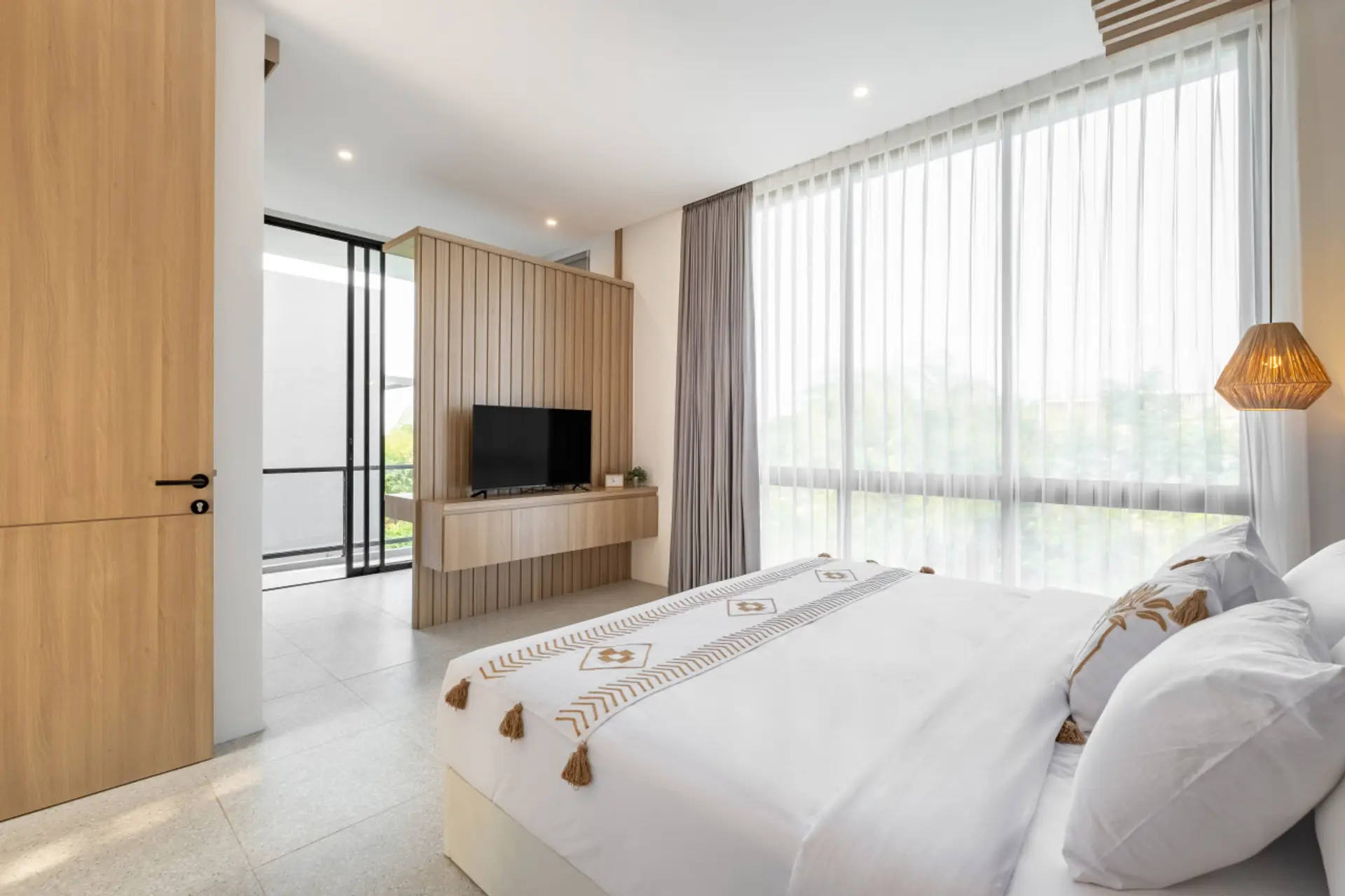 Bright and cozy bedroom with a panoramic green view and natural wood accents.