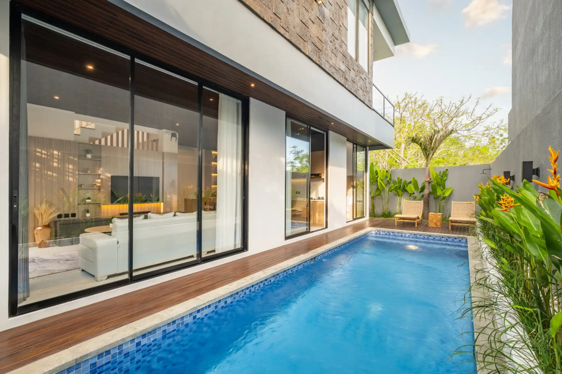 Private plunge pool area with tropical greenery, wooden deck, and cozy sun loungers — perfect for relaxing in a serene outdoor retreat.