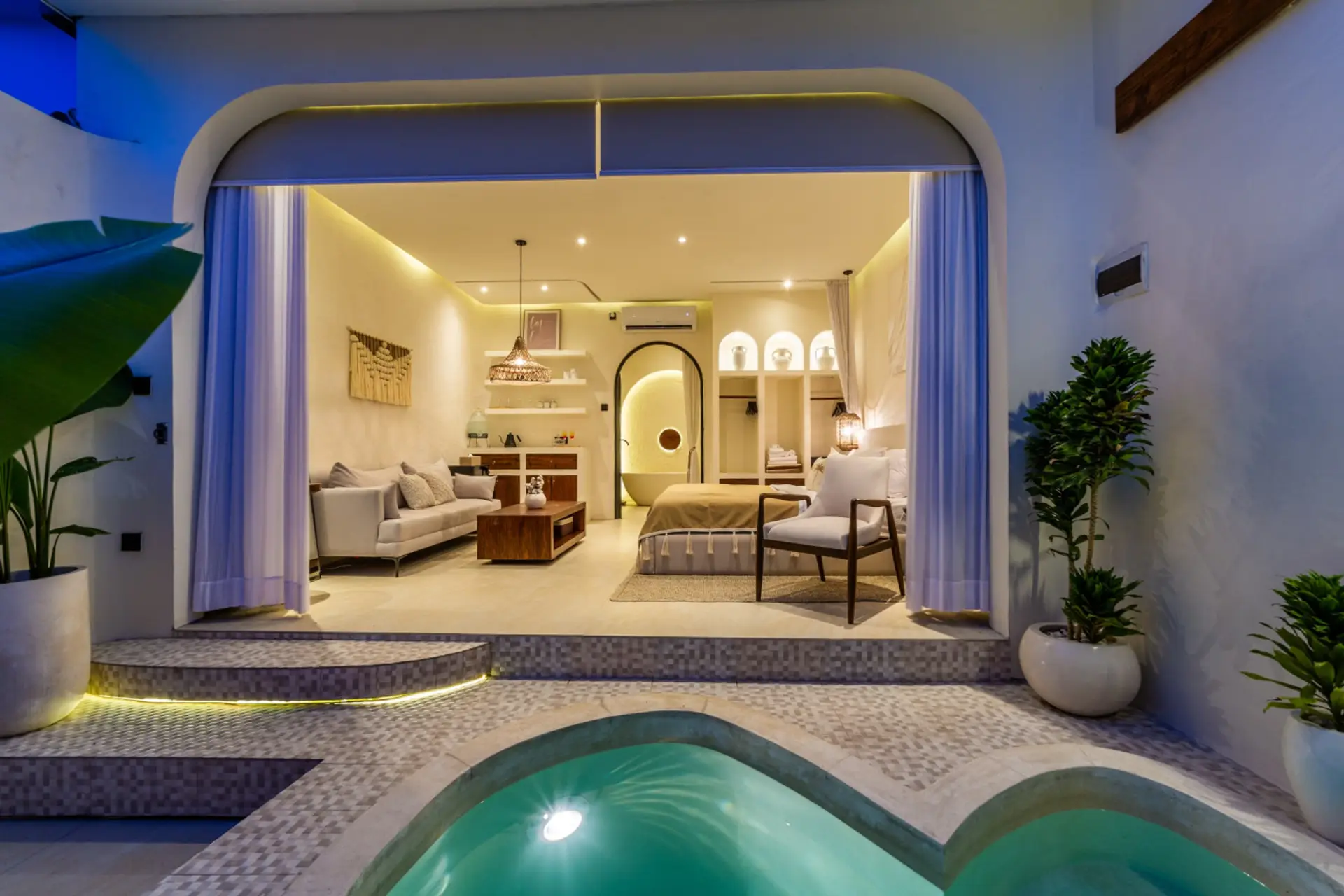 Tropical villa bedroom opening to a private patio with a plunge pool and plants.