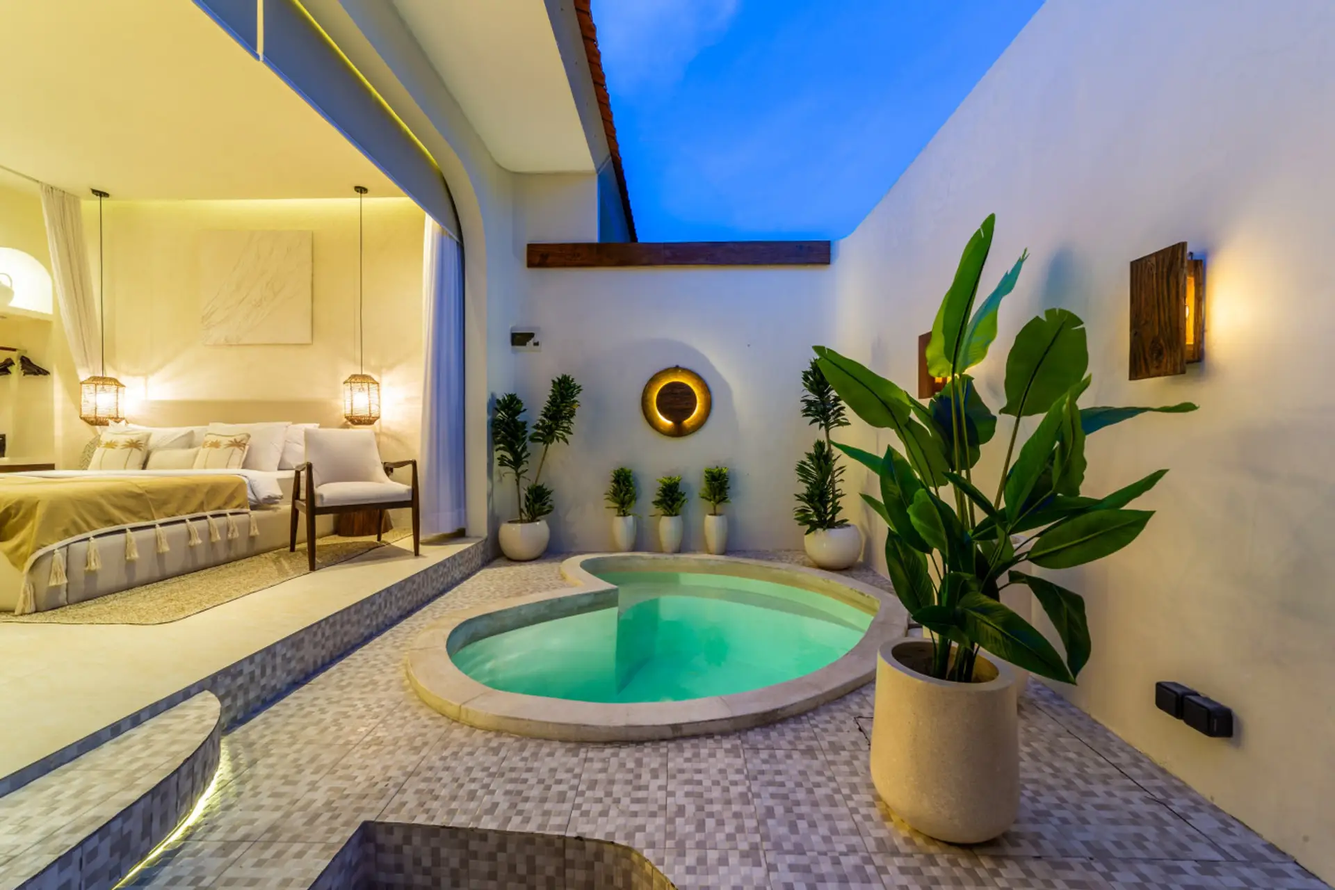 Tropical villa bedroom opening to a private patio with a plunge pool and plants.