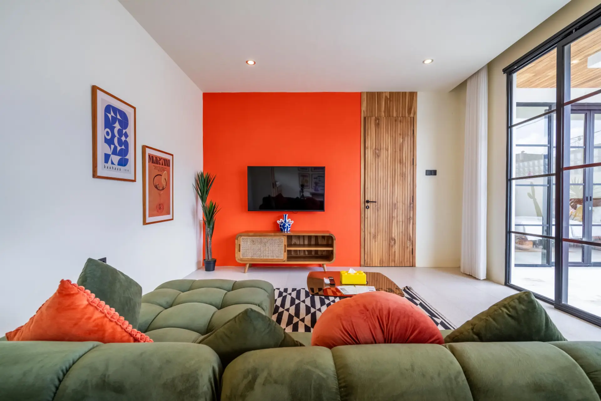 vibrant living room features a large, olive green sectional sofa with orange and red throw pillows in the foreground.