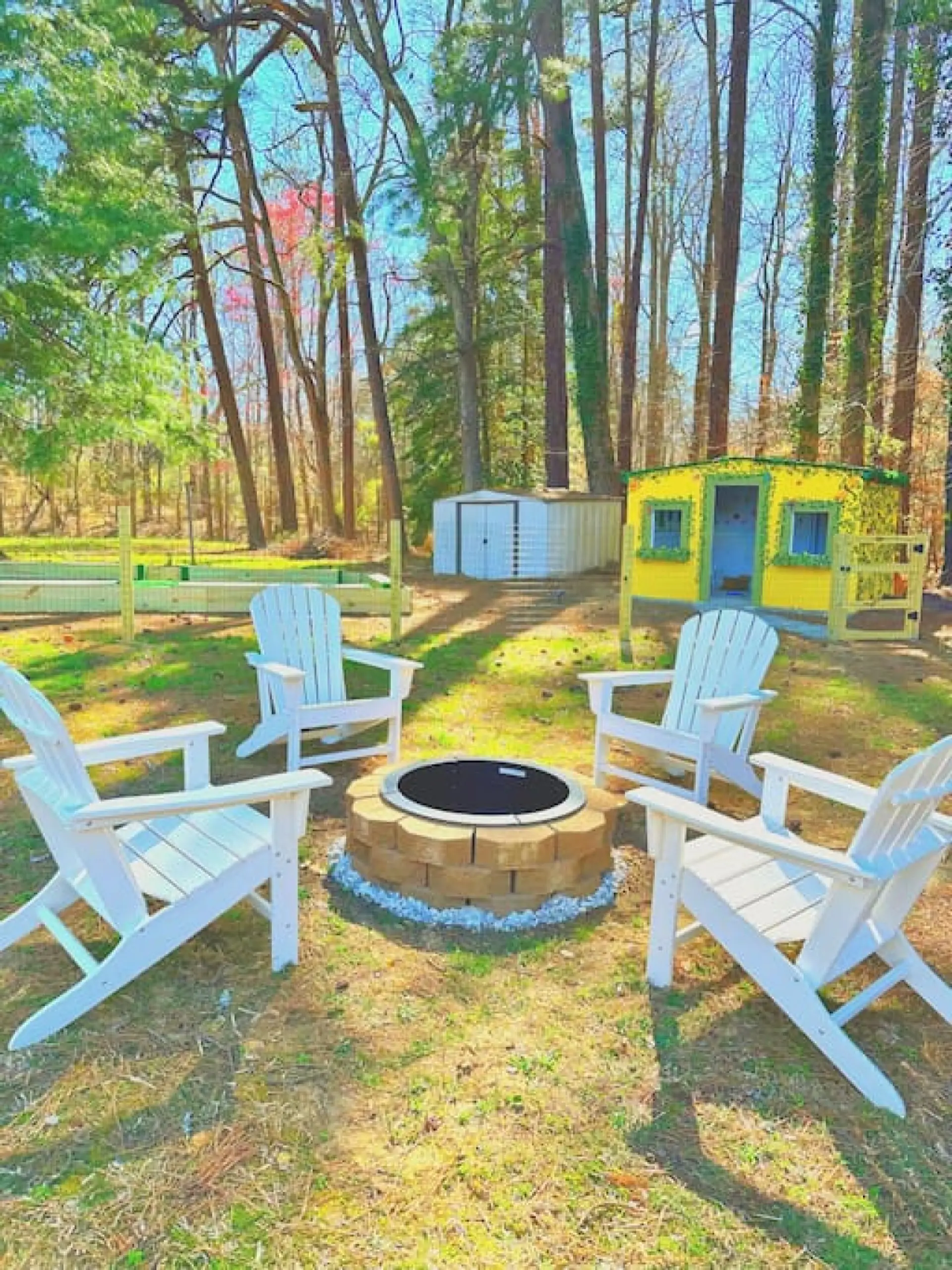 A fully fenced-in backyard featuring a kid-sized life playhouse, fire pit, soccer pool, corn hole boards, archery range, tetherball, and more!