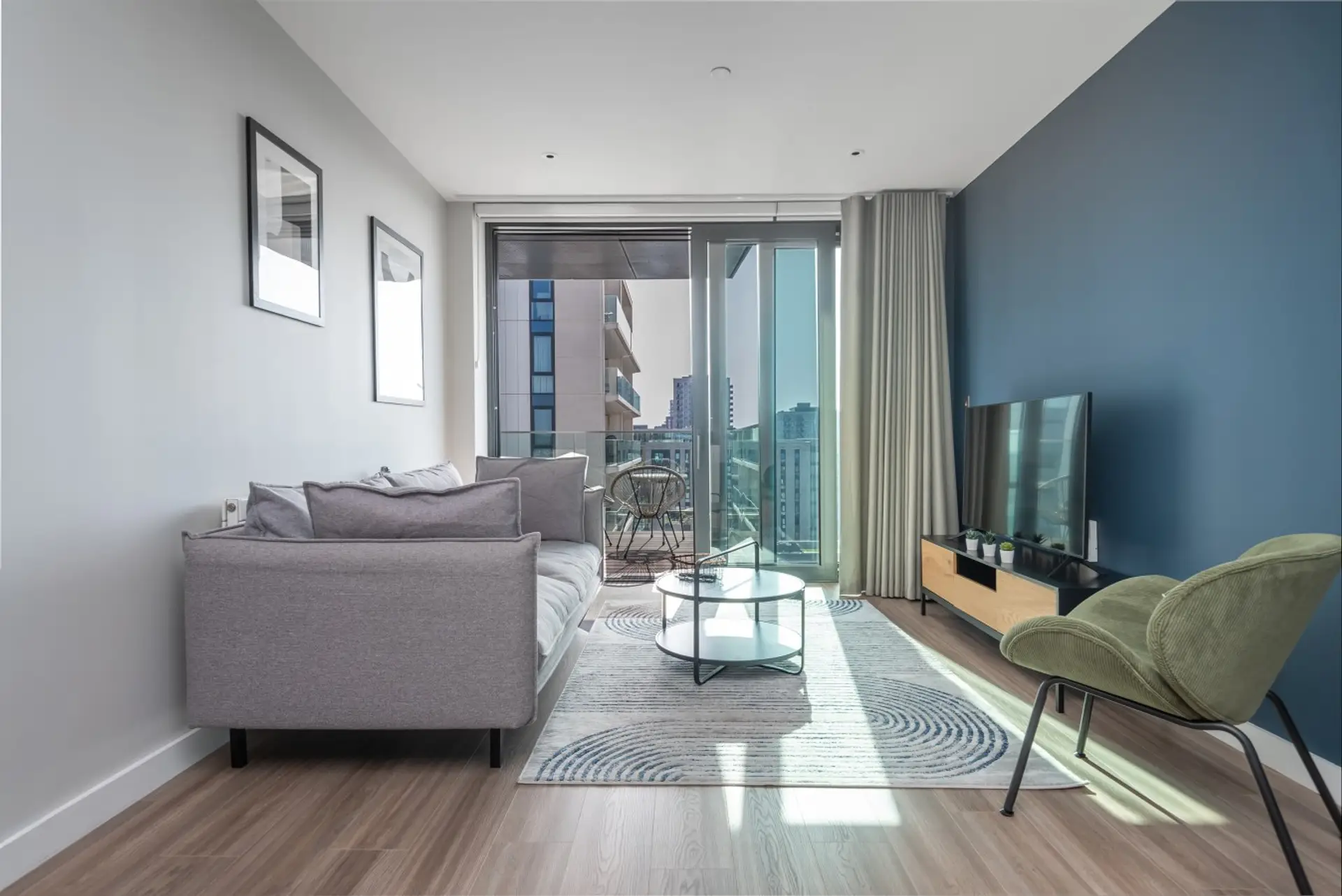 Bright, modern living room with comfy sofa, TV and balcony city views