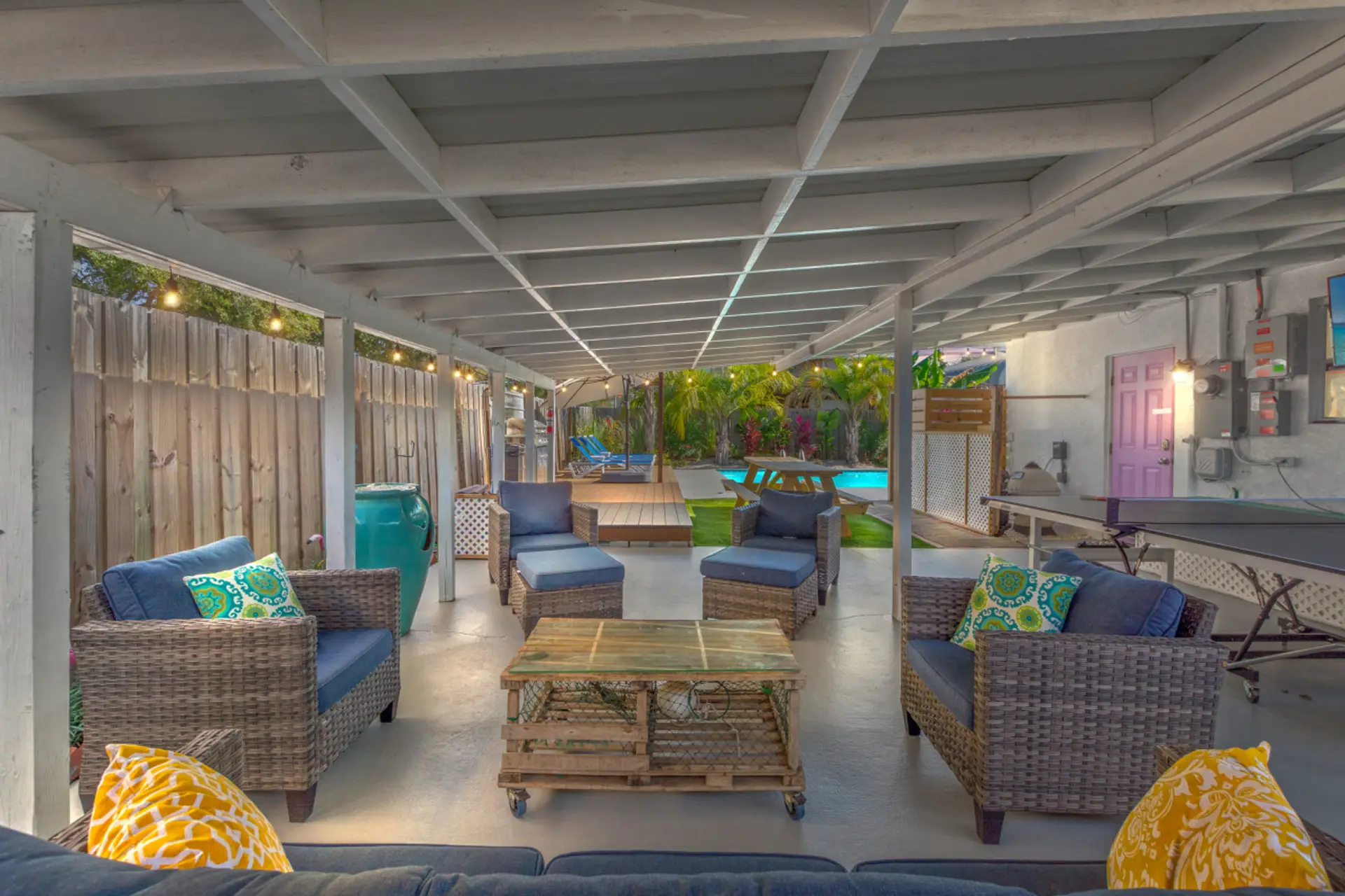 Lots of covered outdoor seating with a peaceful water feature, Edison lights, outdoor TV, and ping pong table.