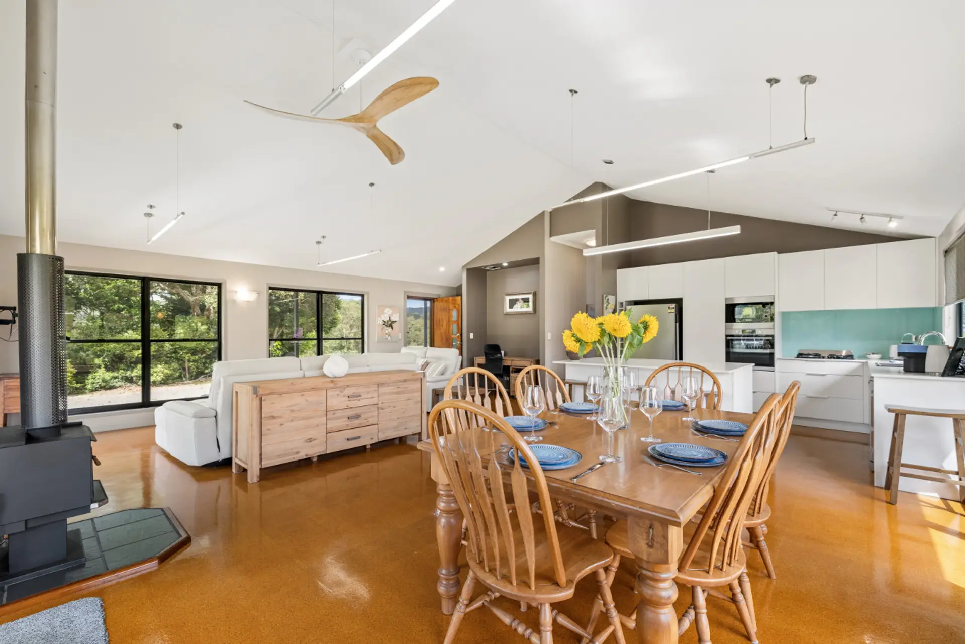 Open-plan kitchen, living and dining areas with wood fireplace and balcony access