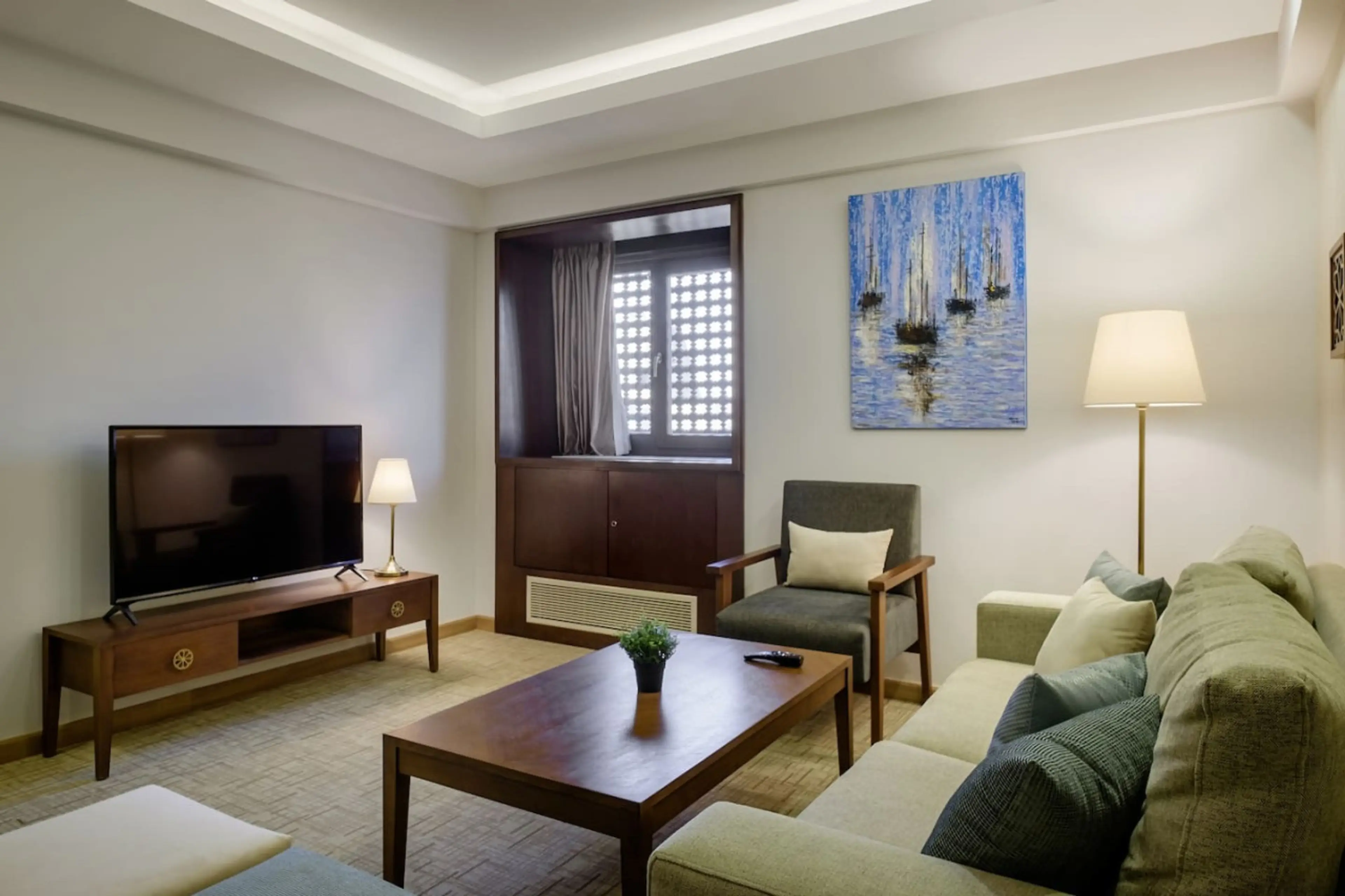 Your cozy corner! A comfy sofa bed, chairs, and a Smart TV—all bathed in natural light from the window.
