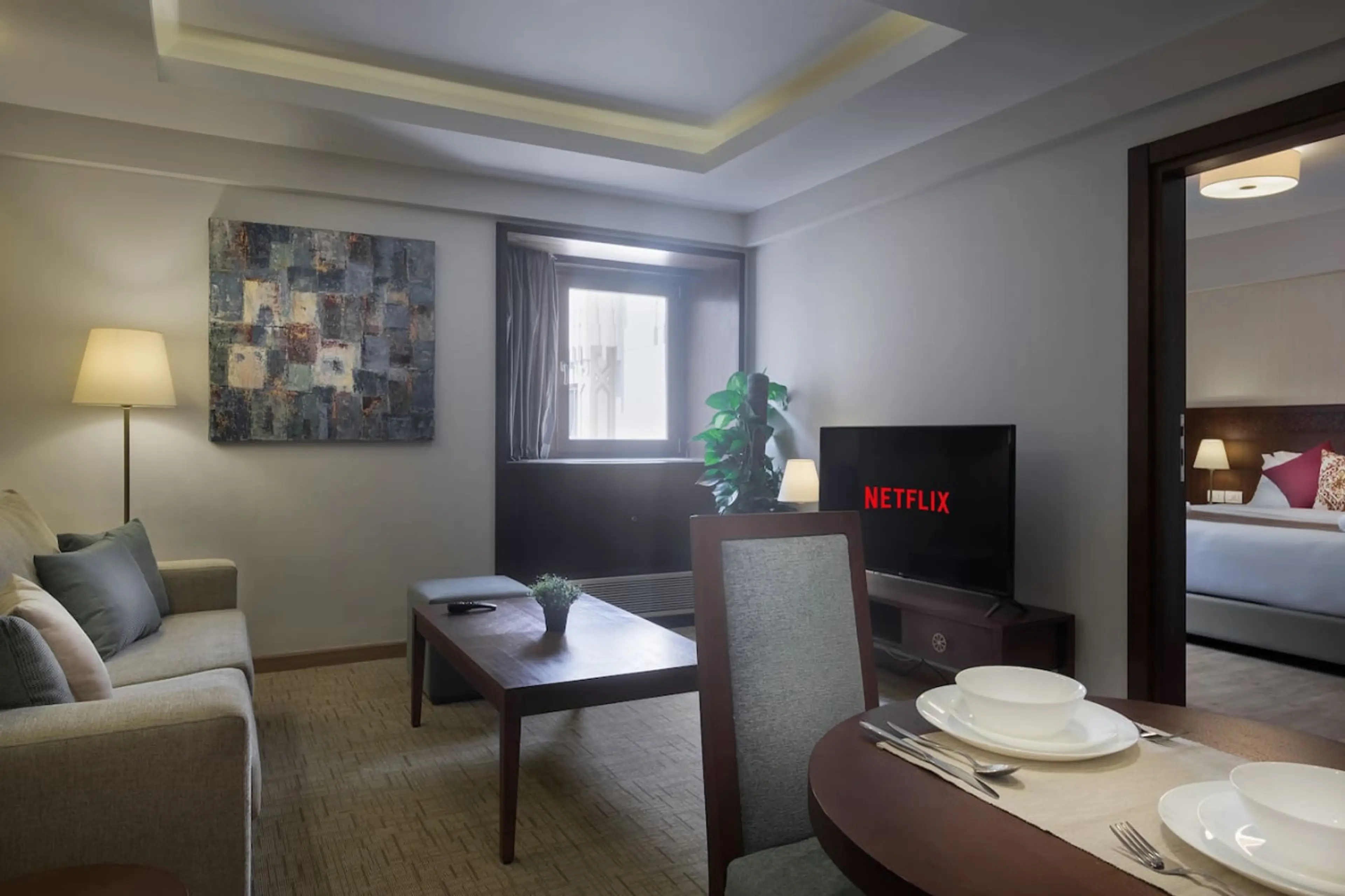 Your cozy corner! A comfy sofa bed, chairs, and a Smart TV—all bathed in natural light from the window.