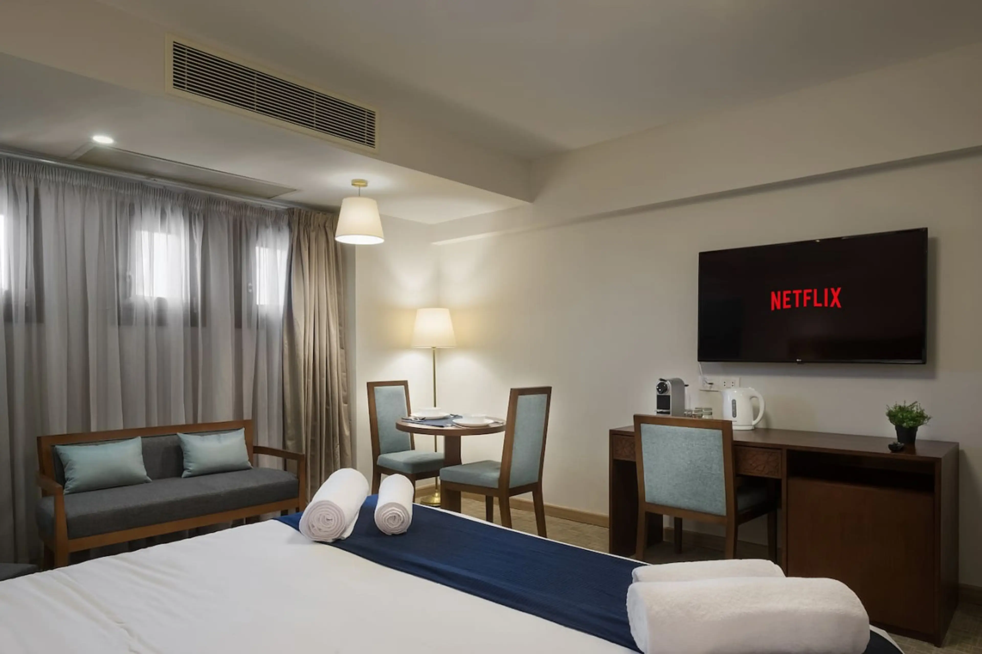 All-in-one comfort! A cozy bed, desk with a coffee station, Smart TV, and a dining spot—perfectly laid out.