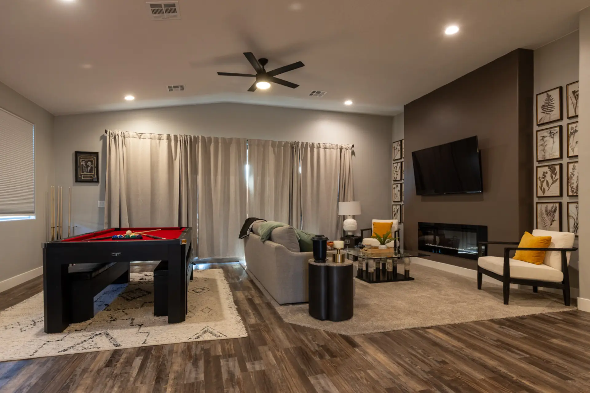 Open concept living area with pool table, fire place, comfortable seating and classy decor.
