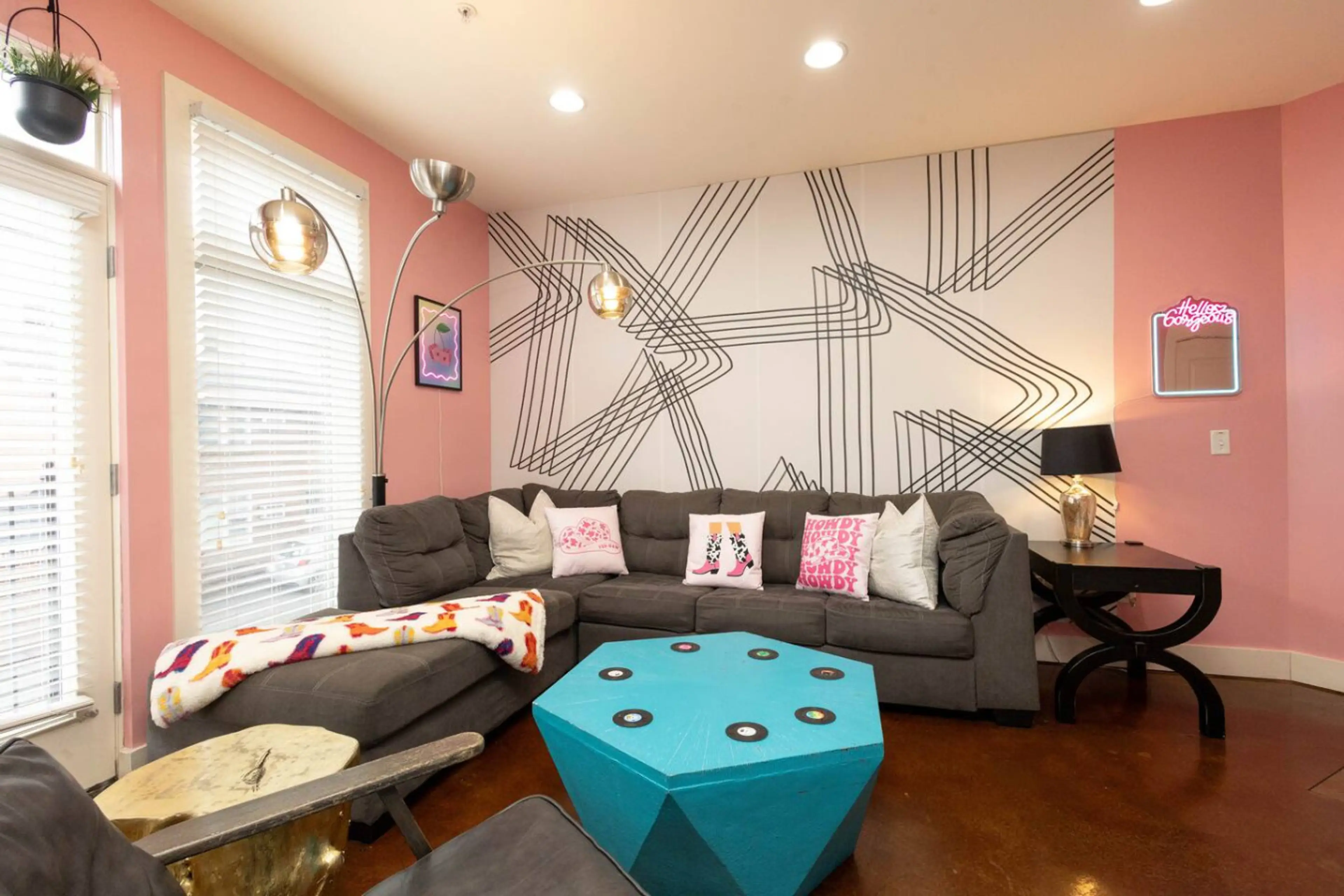A modern twist on cowgirl glam! This space features a bold accent wall, a huge sectional sofa, and a funky turquoise gem-shaped coffee table. The perfect backdrop for selfies, games, or movie nights.