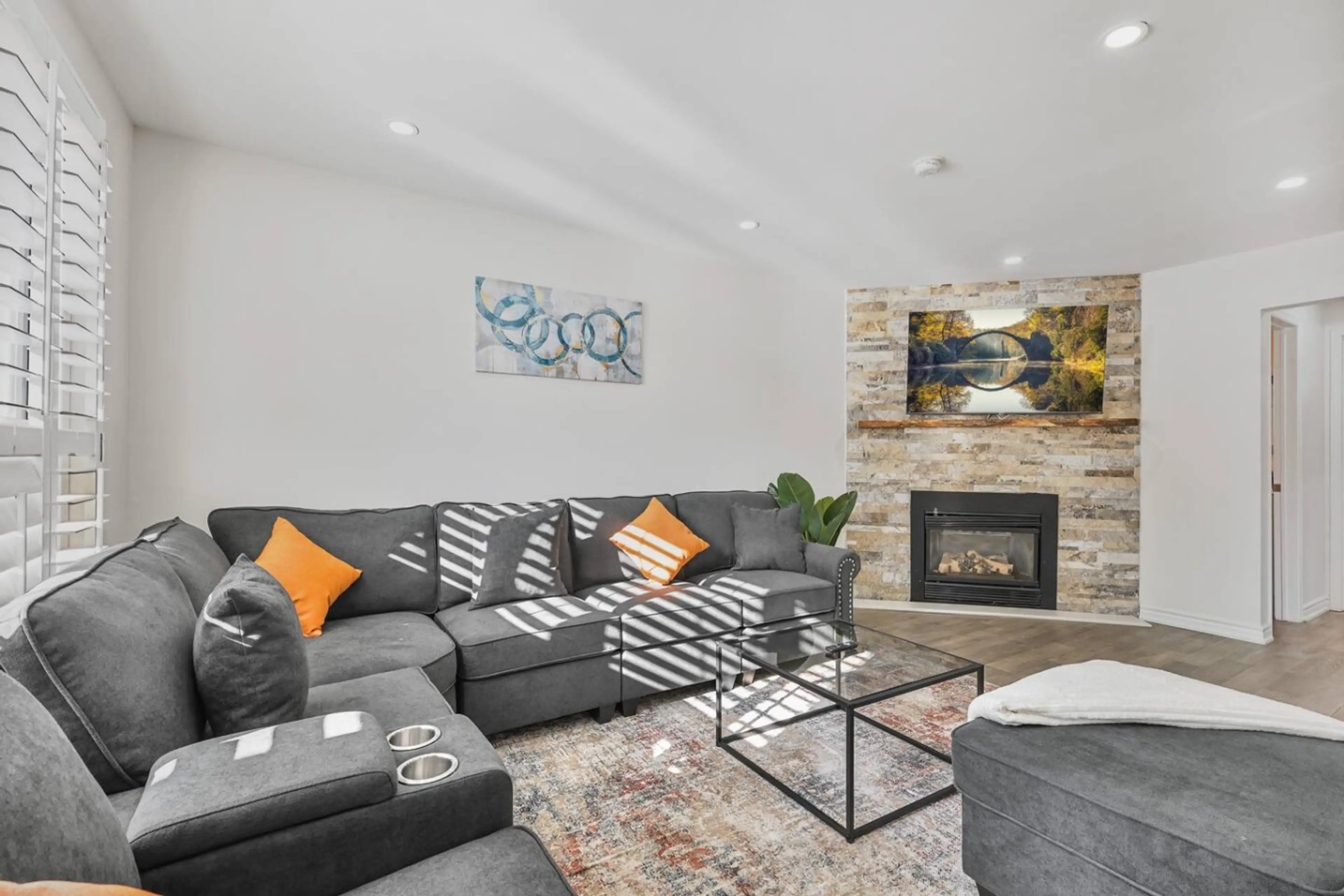 Cozy up in the stylish living room. Plush sectional for movie nights, a modern gas fireplace for warmth, and natural light streaming through the shutters. The perfect spot to unwind after a day out.