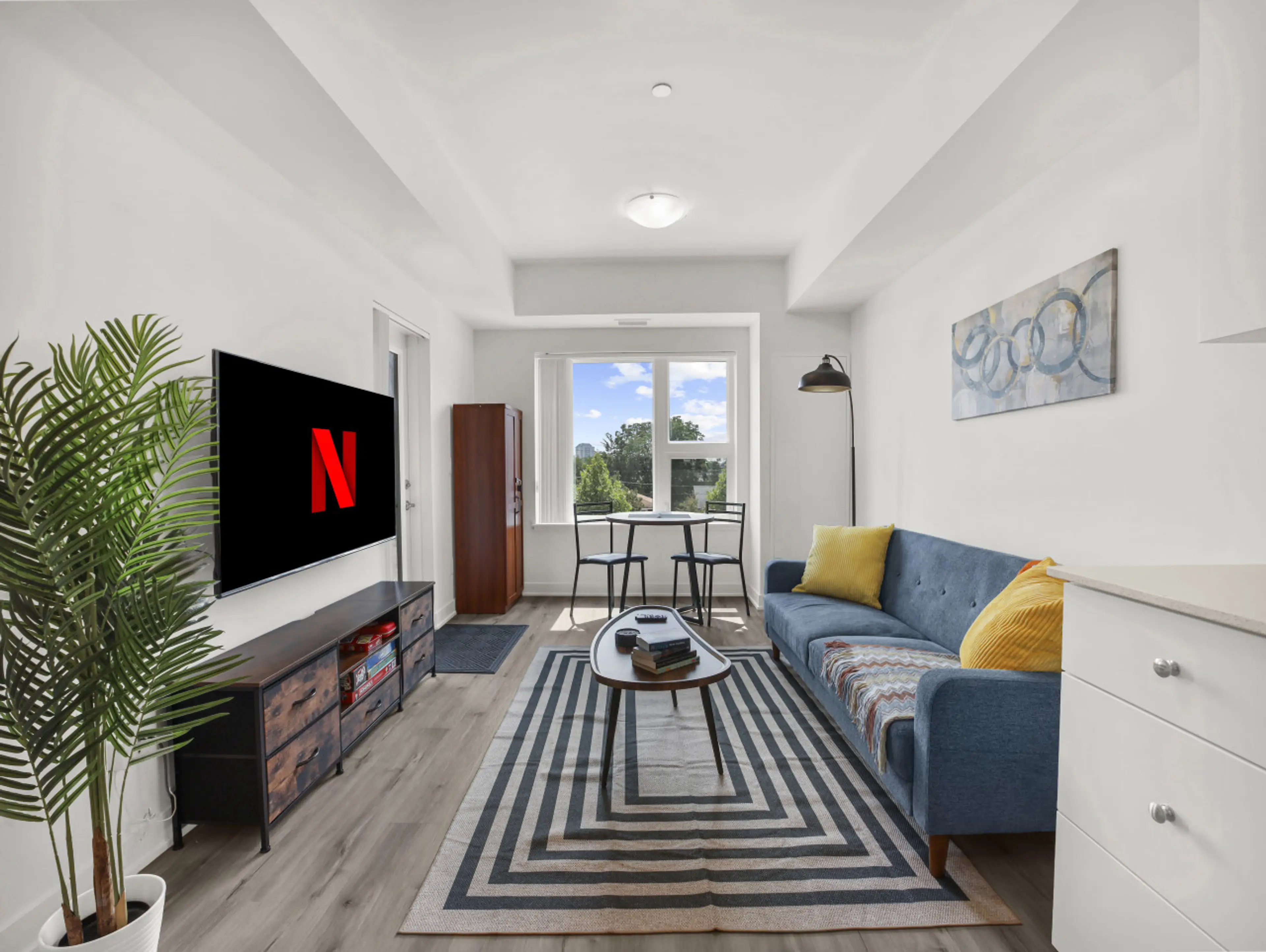Relax in style. Enjoy the modern, light-filled living area featuring a cozy blue sofa, smart TV with Netflix, and stylish decor. The perfect spot to unwind after a day of exploring.