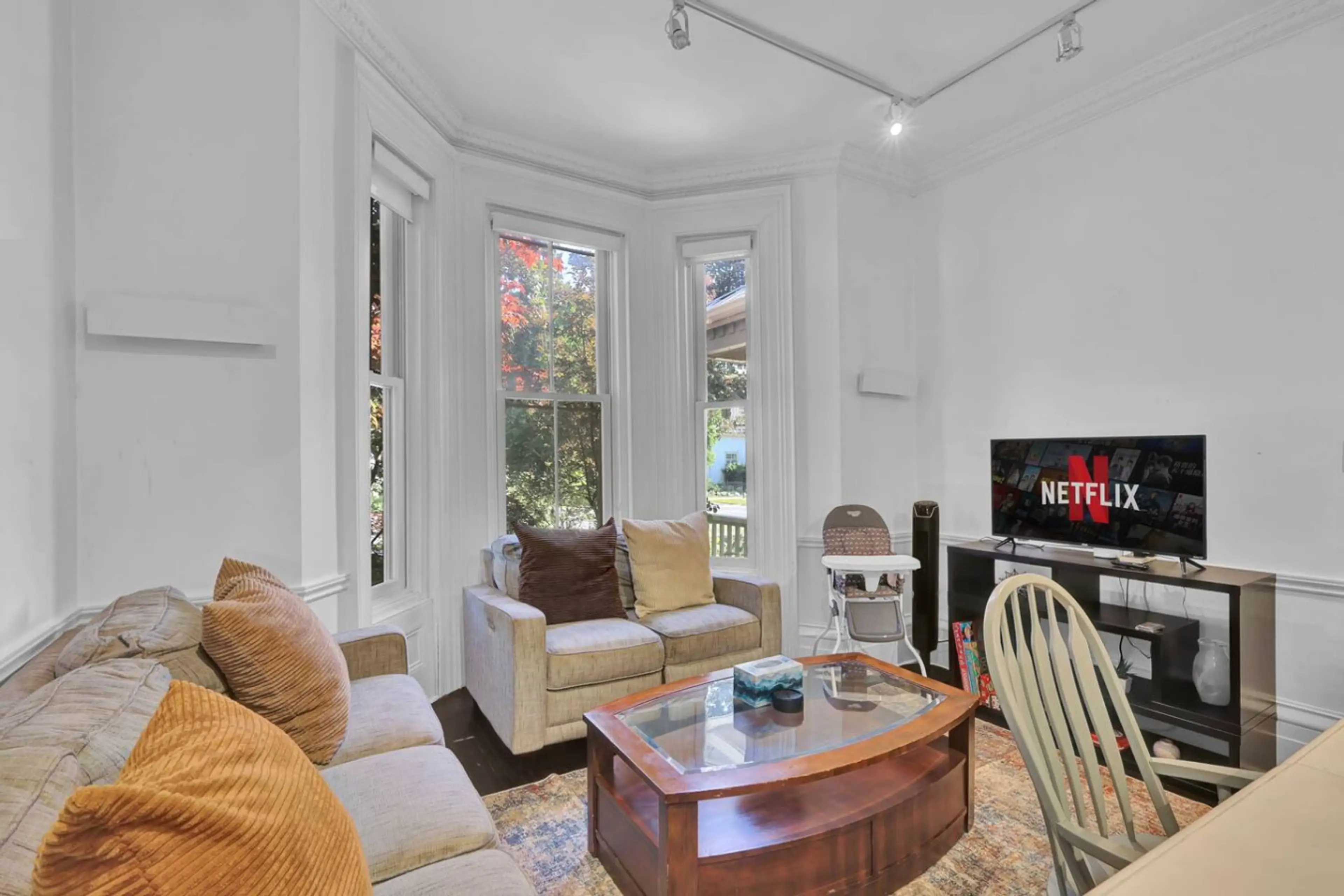 Unwind in a bright living area where historic charm meets modern comfort. Large bay windows invite natural light and seasonal views into this cozy retreat. It is the perfect spot for quiet mornings or relaxing movie nights.