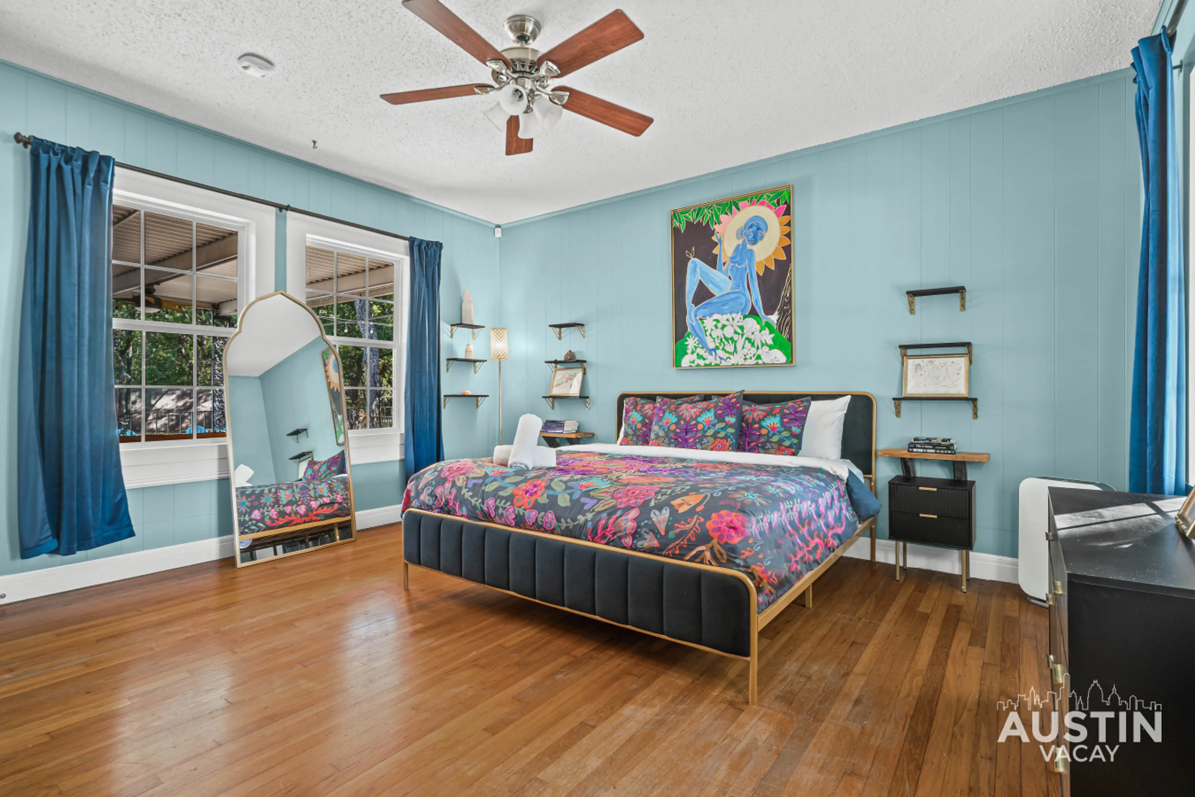 Stylish king bedroom with vibrant art and custom linens.