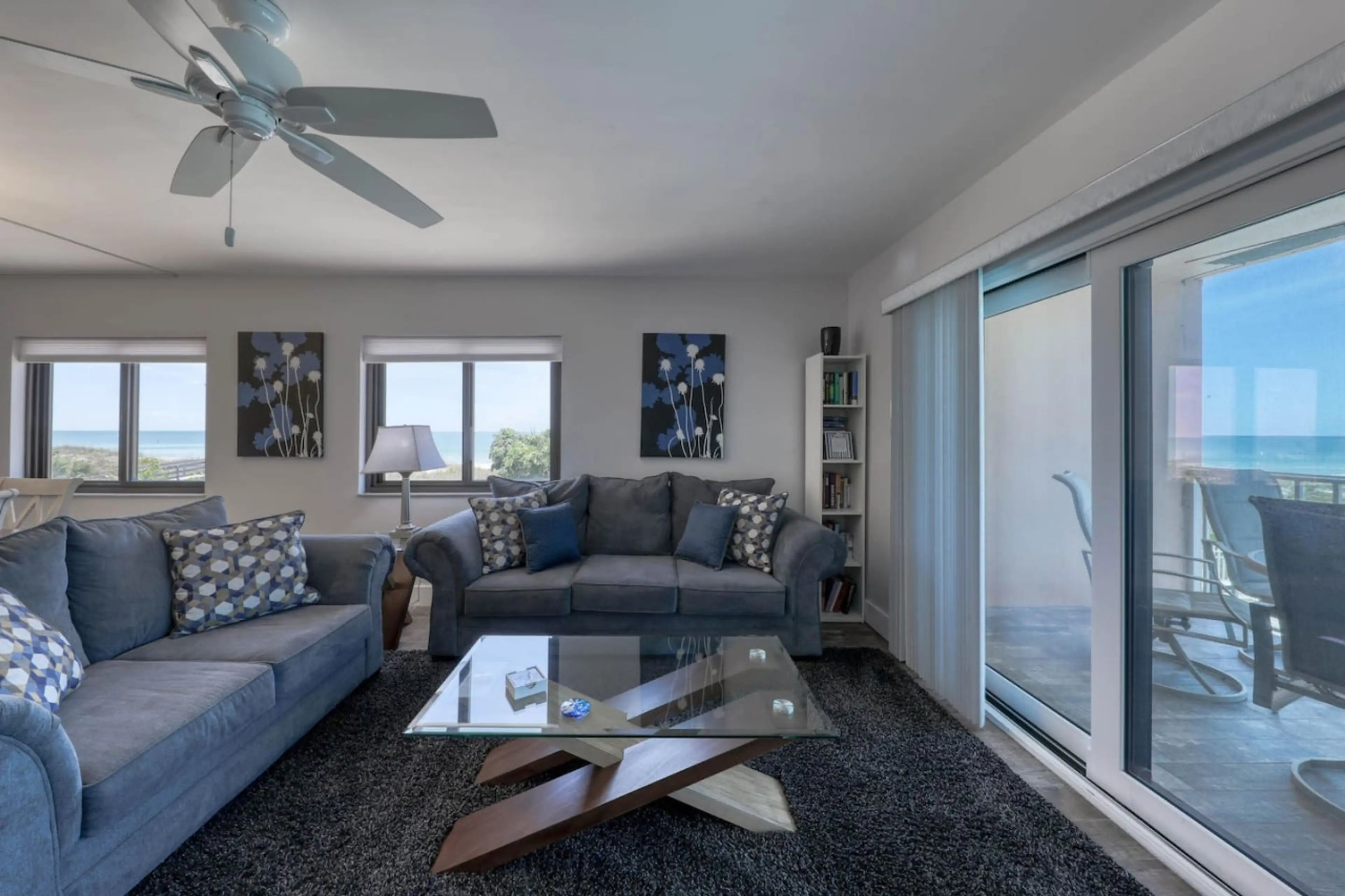 Cozy living room w/ plush seating, ceiling fan, & sliding doors letting in natural light.