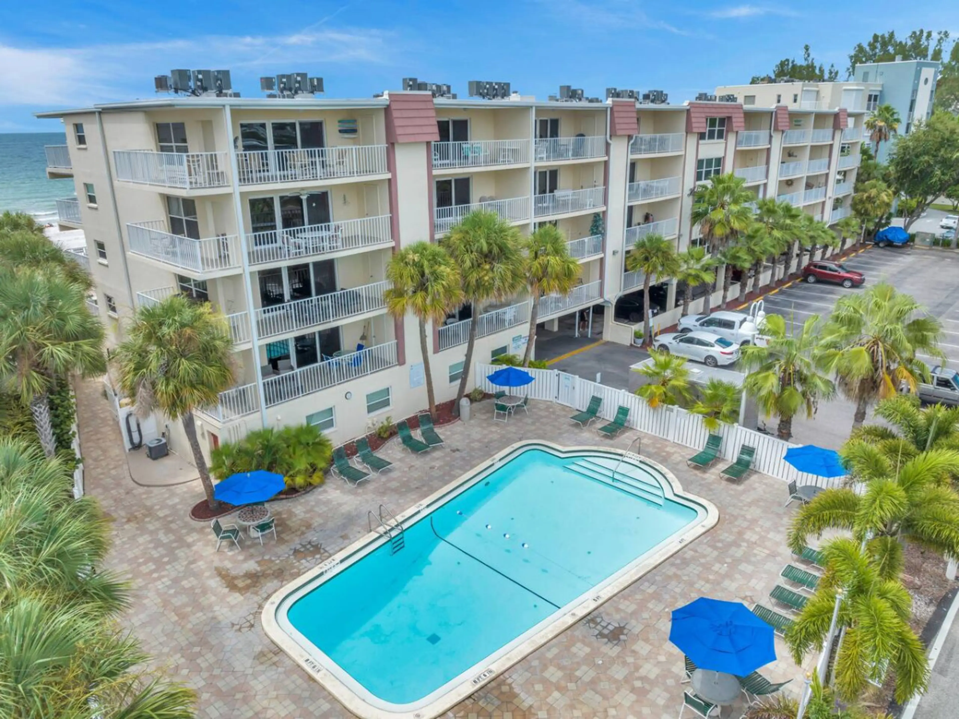 Resort-style pool area surrounded by palm trees & sunny lounge spaces.