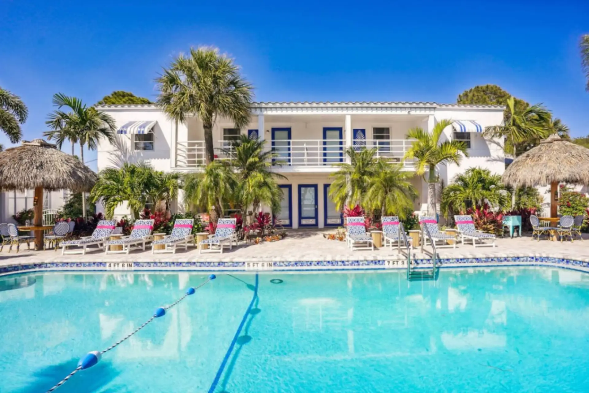 Sun-soaked pool surrounded by palm trees, lounge chairs, & bright resort-style vibes.