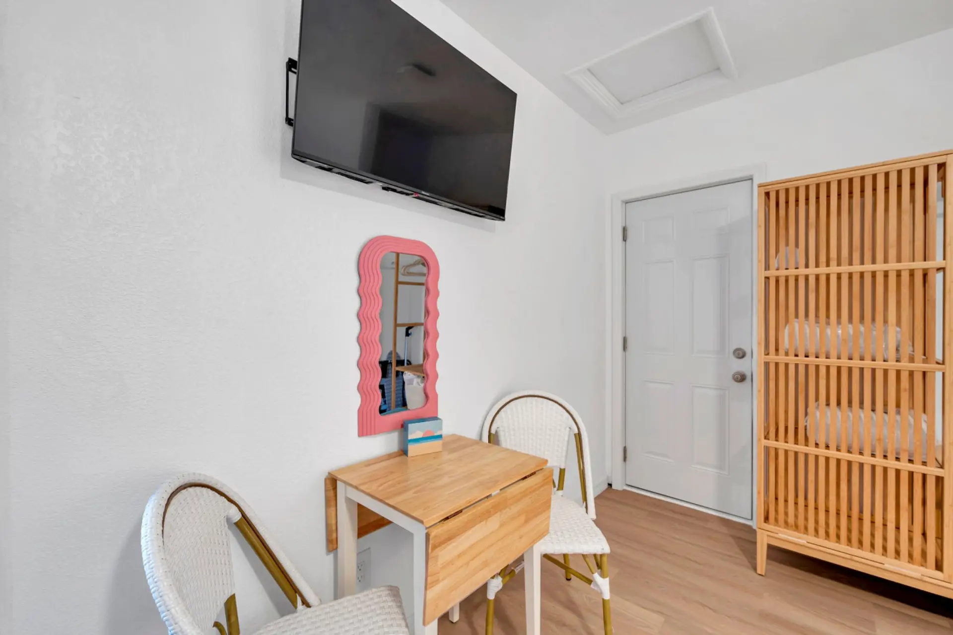 Bright entry area w/ a cozy table, wavy mirror & woven chairs for a warm welcome.