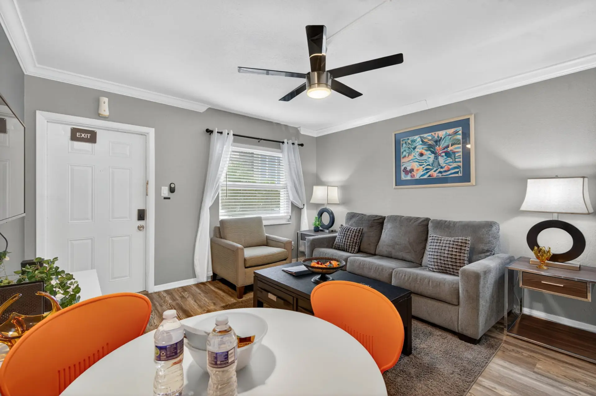 Bright living area w/ comfy seating, ceiling fan, & cheerful pops of color for easy lounging.