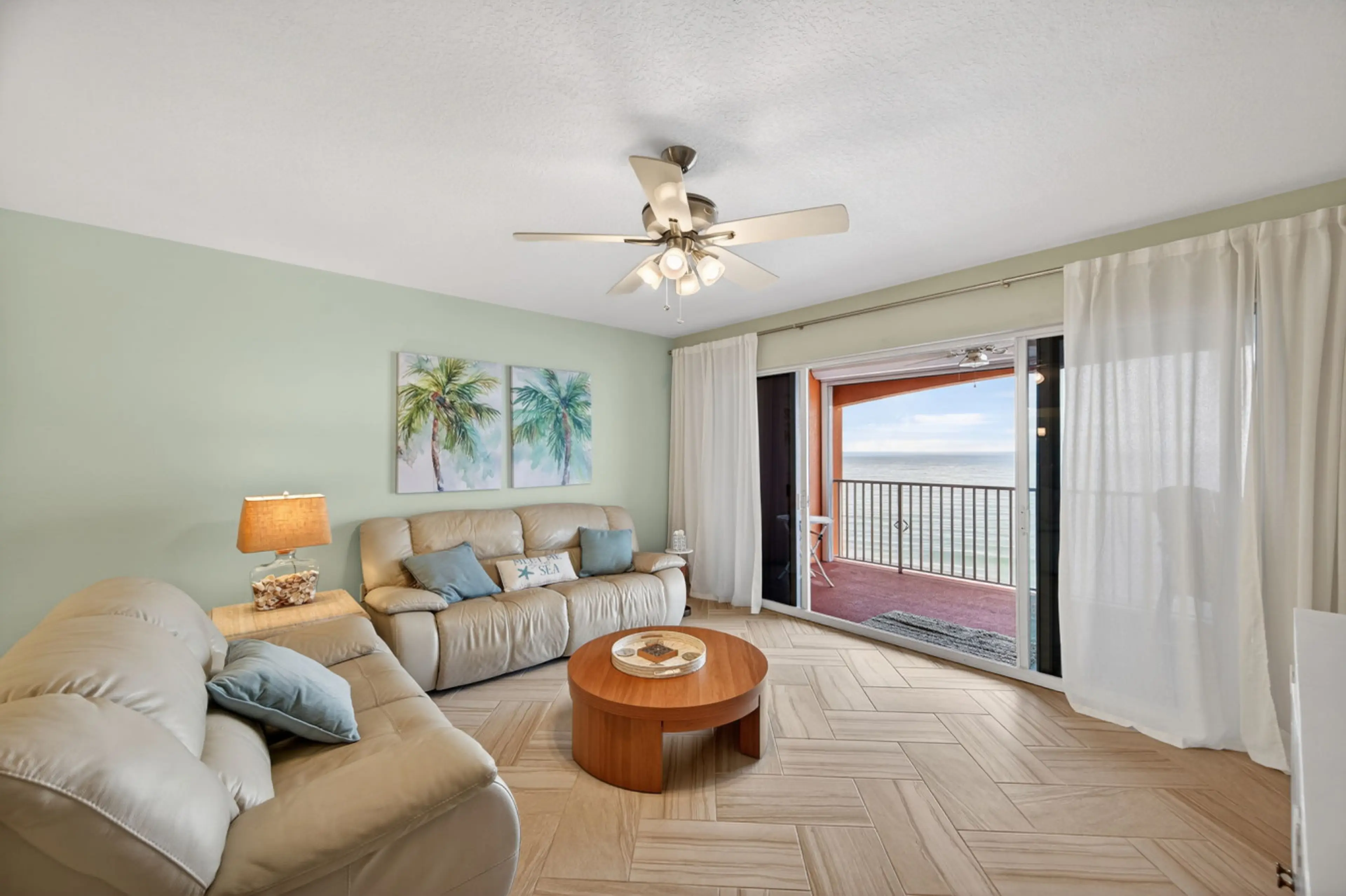 Bright living room w/ comfy seating, ceiling fan & sliding doors opening to the balcony.