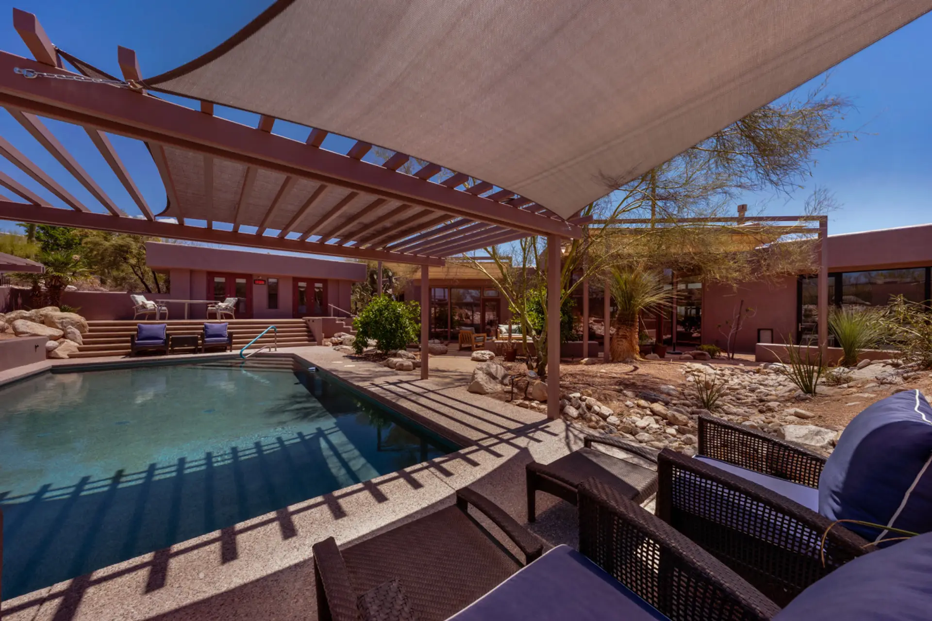 Resort-style backyard with a private pool, shaded lounge areas, and beautiful desert landscaping