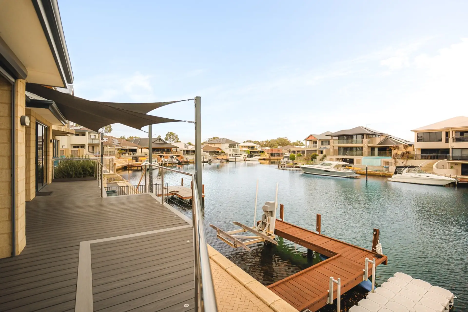 Waterfront deck with canal views, shade sails, glass railing and private jetty access for a relaxing Halls Head holiday stay.