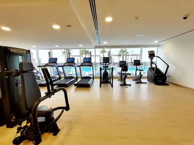 Shared gym with treadmills and cardio machines facing the pool