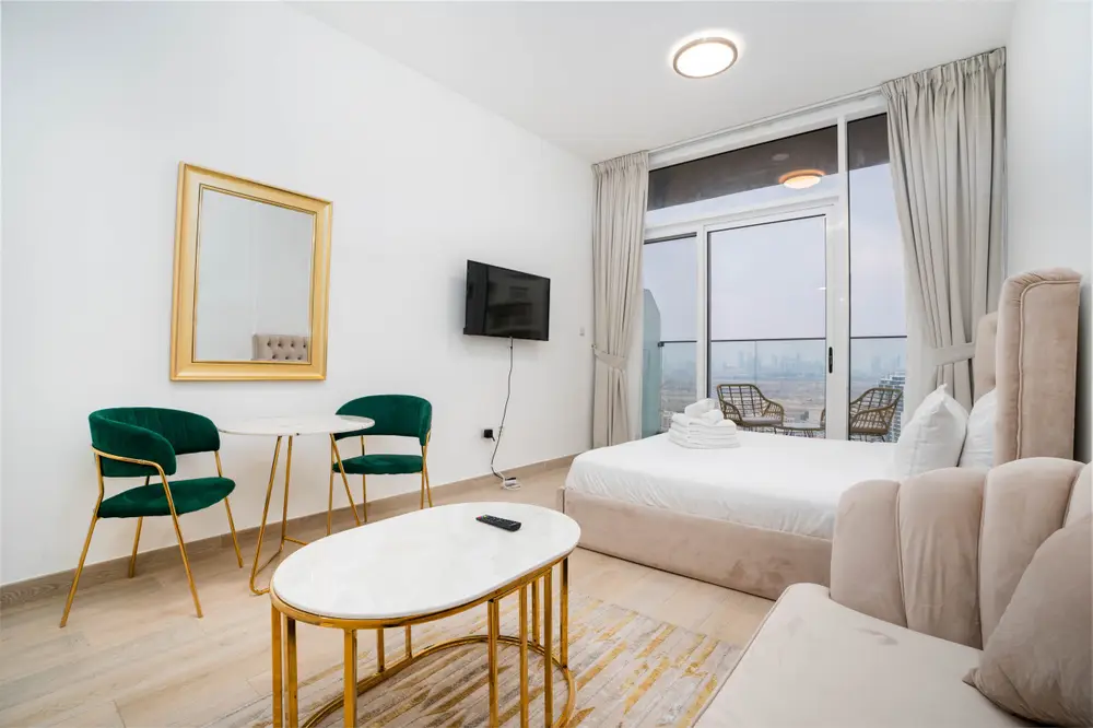Studio with double bed, velvet sofa, green chairs, wall TV and balcony door