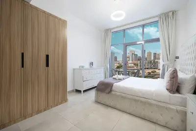 Main bedroom with a large fitted wardrobe, white dresser and city view through the window