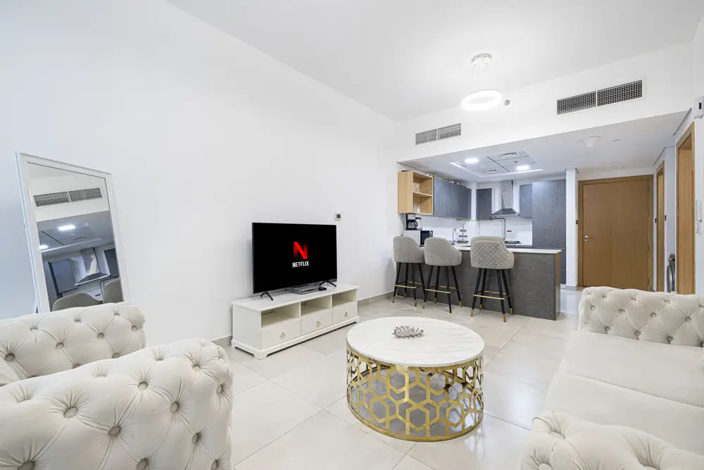 Living room toward the kitchen with sofas, TV and bar counter in an open-plan layout