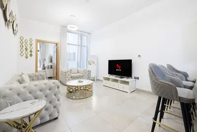 Living room with tufted sofas, gold coffee table, wall TV and bar stools