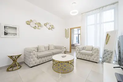 Living room from the far wall: tufted sofas, gold side tables and round wall plates