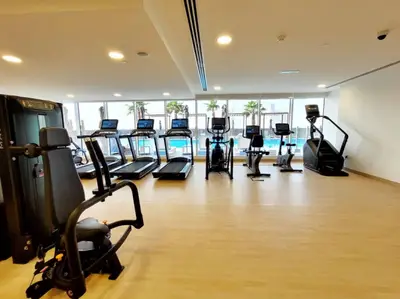 Bright shared gym with rows of treadmills overlooking the pool