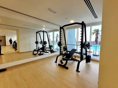 Squat rack and bench in the gym with the pool visible outside