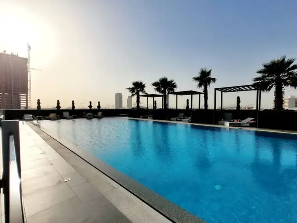 Palm-lined outdoor pool with shaded seating and skyline backdrop