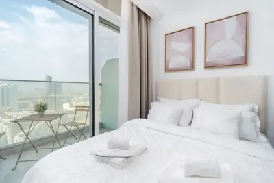 Queen bed by the window with skyline views and a balcony bistro set