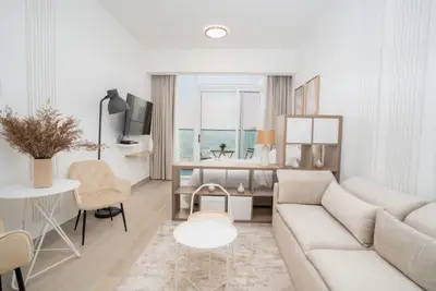 Bright living area with beige sofa, round tables and mounted TV