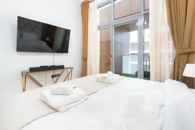 Wall-mounted TV at the foot of the bed beside the terrace door